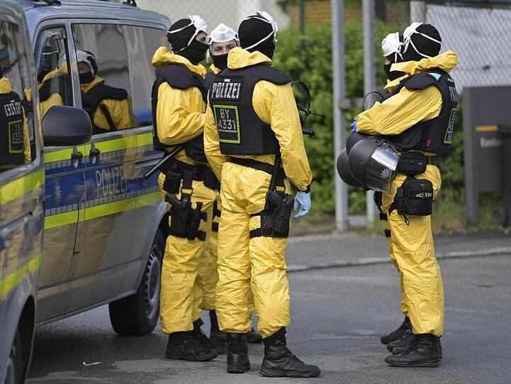 Polizeikräfte in Schutzkleidung sichern die Verlegung von Bewohnern einer Asylbewerberunterkunft. Foto: Uwe Lein/dpa