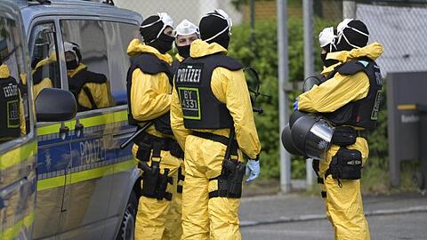 Polizeikräfte in Schutzkleidung sichern die Verlegung von Bewohnern einer Asylbewerberunterkunft. Foto: Uwe Lein/dpa