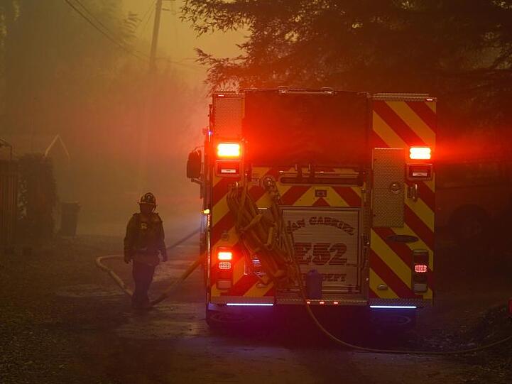 Ein Feuerwehrmann steht neben einem Einsatzwagen. Kalifornien kämpft um die Eindämmung riesiger Waldbrände und hat nun auch Hilfe aus dem In- und Ausland angefordert.