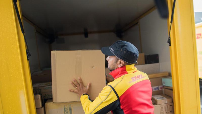 Ein Paketzusteller stellt ein Paket in ein Fahrzeug der Deutschen Post DHL. Ein Paketzusteller stellt ein Paket in ein Fahrzeug der Deutschen Post DHL.