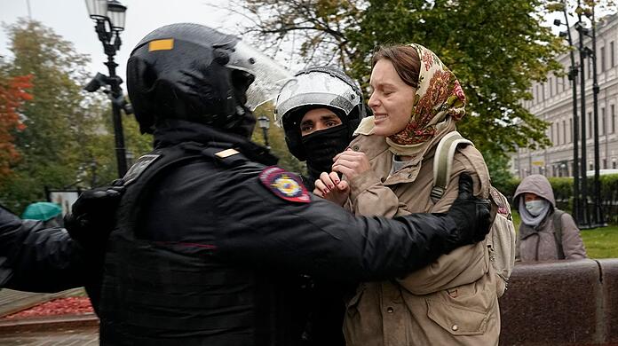 Bei einem Protest gegen die Teilmobilisierung in Moskau halten Polizisten eine Frau fest.