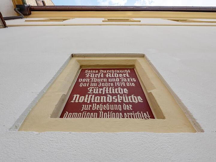 Eine Wandtafel mit einem Text über die Fürstliche Notstandsküche ist am Schloss St. Emmeram eingelassen. Foto: Armin Weigel/Archivbild
