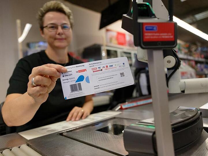 Eine Mitarbeiterin in einer Filiale des Einzelhändlers REWE hält ein Blatt mit einem Barcode in der Hand. Mit diesem Abschnitt sollen Bürger in Köln ihre Knöllchen künftig einfach an Supermarktkassen begleichen können.