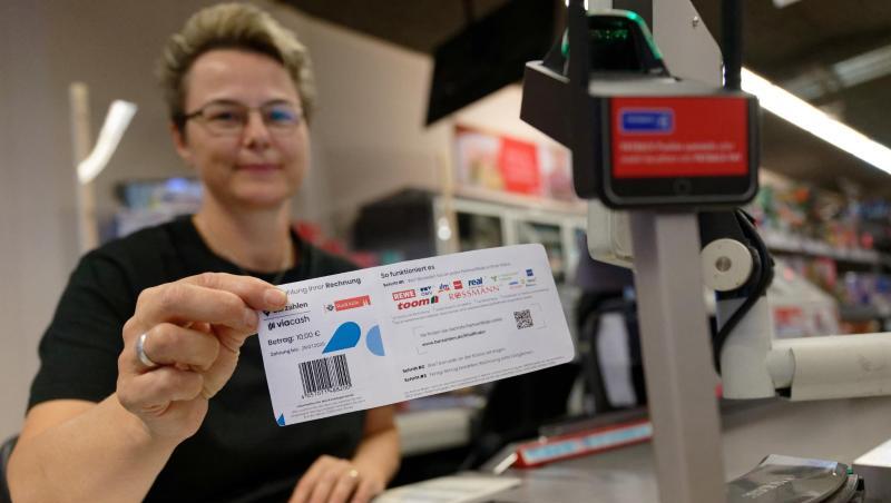 Eine Mitarbeiterin in einer Filiale des Einzelhändlers REWE hält ein Blatt mit einem Barcode in der Hand. Mit diesem Abschnitt sollen Bürger in Köln ihre Knöllchen künftig einfach an Supermarktkassen begleichen können. Eine Mitarbeiterin in einer Filiale des Einzelhändlers REWE hält ein Blatt mit einem Barcode in der Hand. Mit diesem Abschnitt sollen Bürger in Köln ihre Knöllchen künftig einfach an Supermarktkassen begleichen können.