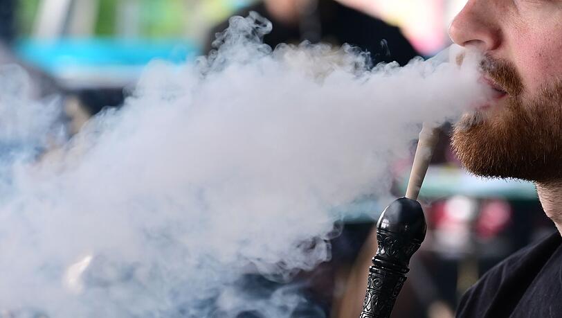 Ein Mann raucht in einer Shisha-Bar eine Wasserpfeife.
