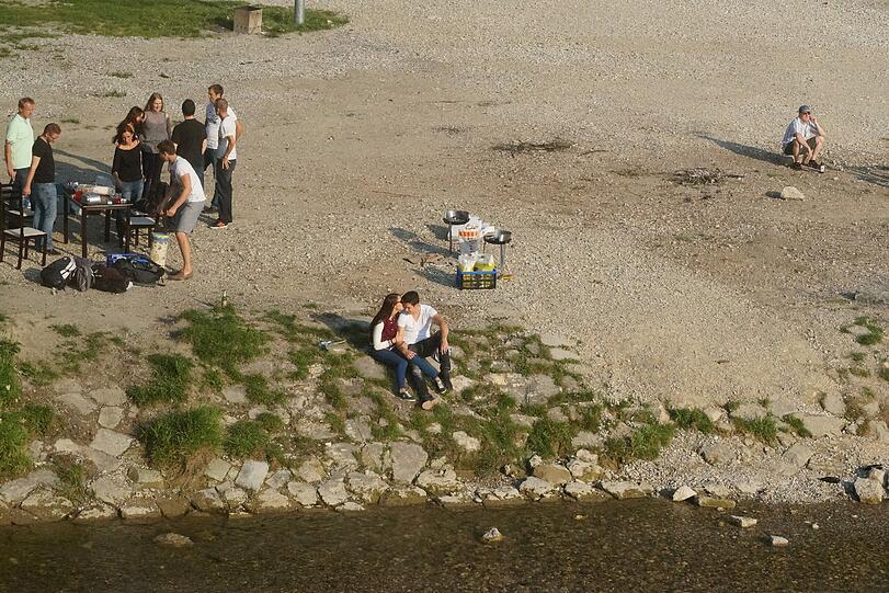 Hinter ihnen wird der Grill angeschmissen.
