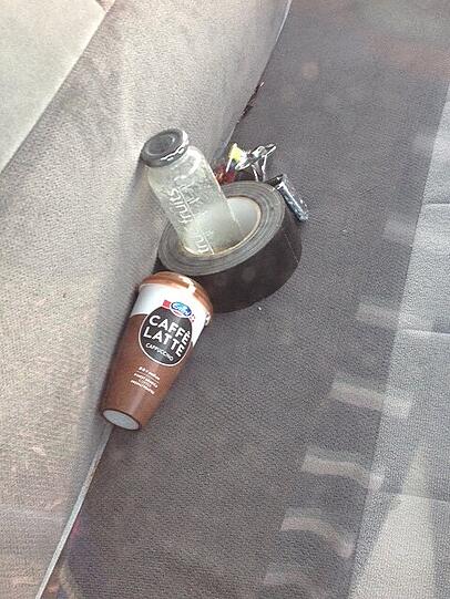 Ein Blick auf den Beifahrersitz: Eine Smoothie-Flasche, ein Kaffee-Becher und eine Rolle Klebenad liegen im Wagen.