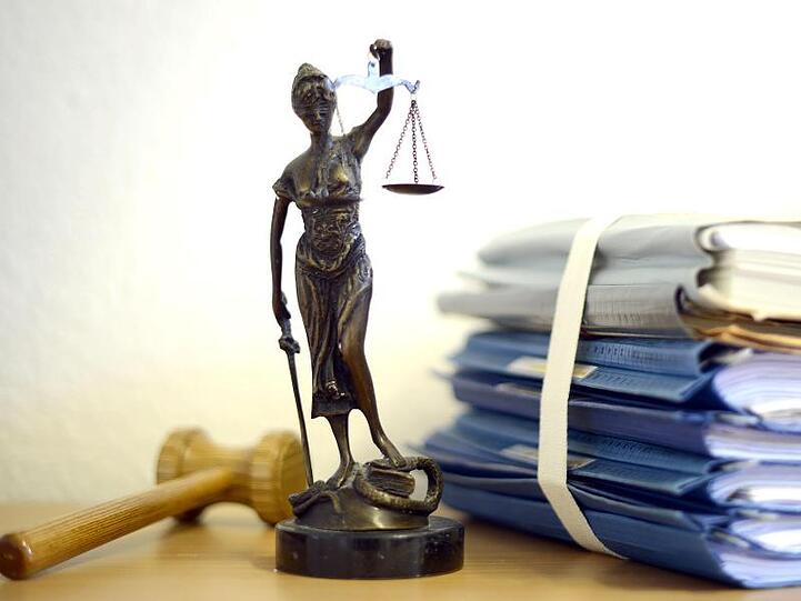 Justitia mit Holzhammer und Aktenstapel. Foto: Volker Hartmann/dpa/Symbolbild