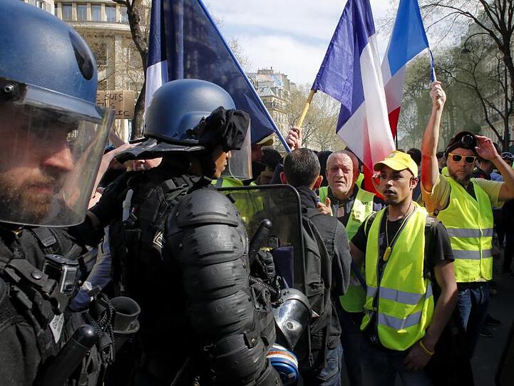 Polizisten vor Demonstranten und Anhängern der "Gelbwesten"-Bewegung, die an einer Protestkundgebung in Paris teilnehmen.