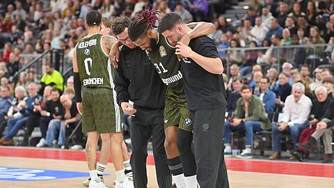 Womöglich schwer verletzt: Devin Booker geht vom Spielfeld und wird dabei von Bayern-Betreuern gestützt. Der US-Amerikaner hat sich am Knie wehgetan.
