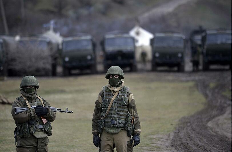 Bewaffnete Soldaten stehen vor einem ukrainischen Militärstützpunkt auf der Krim. Bei einem Sturm auf eine Militärbasis soll ein ukrainischer Soldat getötet worden sein.