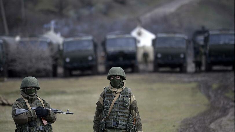 Bewaffnete Soldaten stehen vor einem ukrainischen Militärstützpunkt auf der Krim. Bei einem Sturm auf eine Militärbasis soll ein ukrainischer Soldat getötet worden sein. Bewaffnete Soldaten stehen vor einem ukrainischen Militärstützpunkt auf der Krim. Bei einem Sturm auf eine Militärbasis soll ein ukrainischer Soldat getötet worden sein.