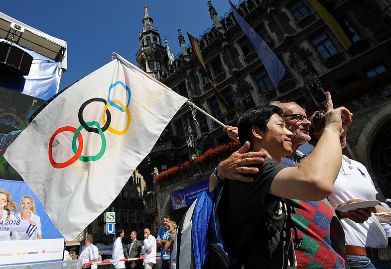 Im Zeichen der Ringe - ein Besucher hält die Olympische Fahne hoch.