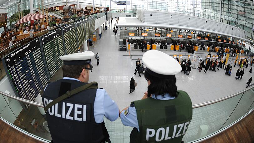 Polizisten beobachten Reisende am Münchner Flughafen. (Symbolbild)