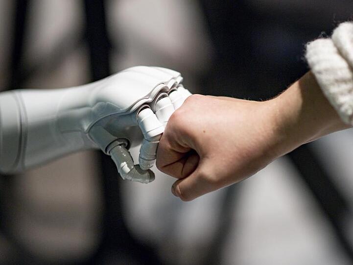 Ein Roboter interagiert mit einer Frau. Foto: Axel Heimken/dpa
