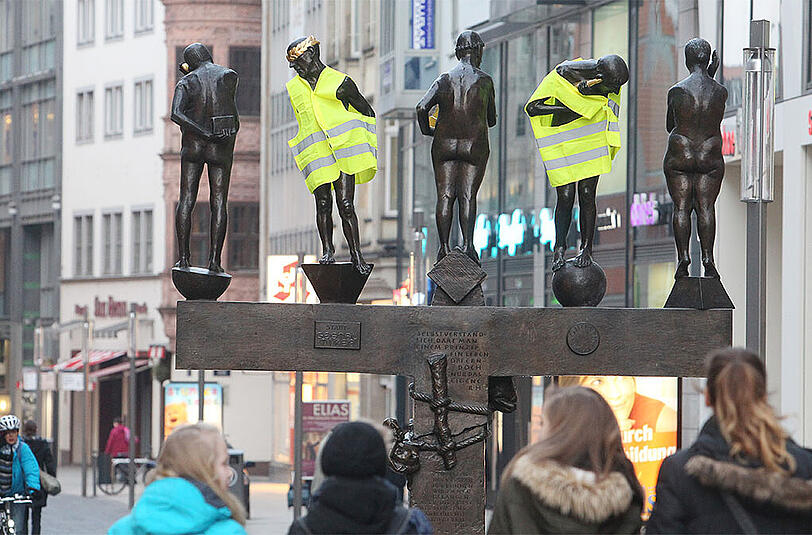 Figuren der Bronzeplastik "Die Unzeitgemäßen Zeitgenossen" des Bildhauers Bernd Göbel in der Fußgängerzone in Leipzig sind als Zeichen des Protestes gegen die islamkritische Bewegung Legida mit Warnwesten versehen.