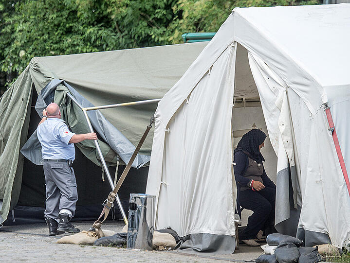Ein Mitarbeiter vom Deutschen Roten Kreuz baut auf dem Gelände der Deggendorfer Erstaufnahmeeinrichtung für Flüchtlinge ein Zelt auf.