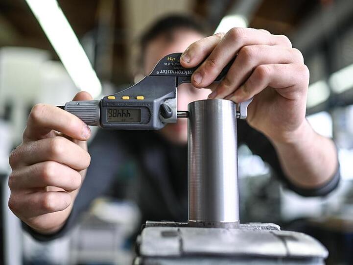 Ein Auszubildender im Metall-Handwerk misst in einem Ausbildungszentrum die Dicke eines Werkstücks.