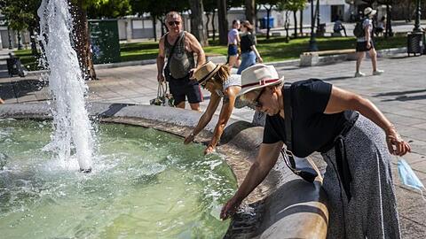 Menschen erfrischen sich bei Temperaturen über 40 Grad mit Wasser aus einem Brunnen auf dem Syntagma-Platz in Athen.
