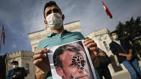 Ein junger Mann hält in Istanbul ein mit einem Schuhabdruck versehenes Foto von Emmanuel Macron in die Kamera.