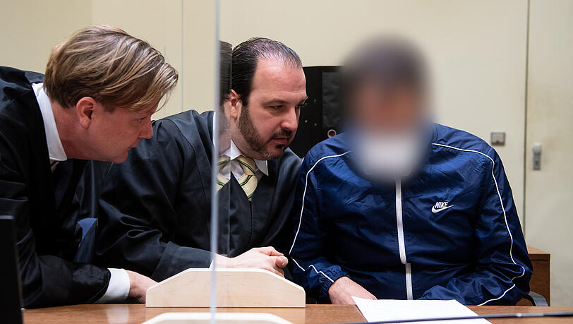 Ein der Männer (r.), die wegen illegalen Waffenhandels angeklagt sind, sitzt vor Prozessbeginn mit seinen Anwälten Nicolas Früsorger (M.) und Michael Weiss im Verhandlungssaal des Landgerichts München I.