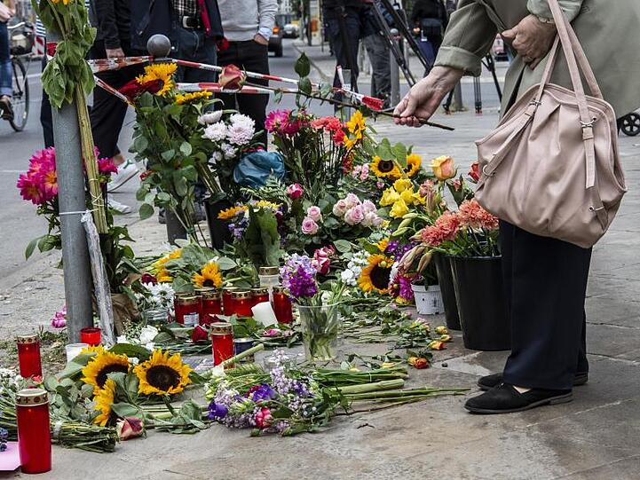 Eine Frau legt Blumen an der Stelle ab, an der vier Menschen bei einem Verkehrsunfall ihr Leben verloren hatten.