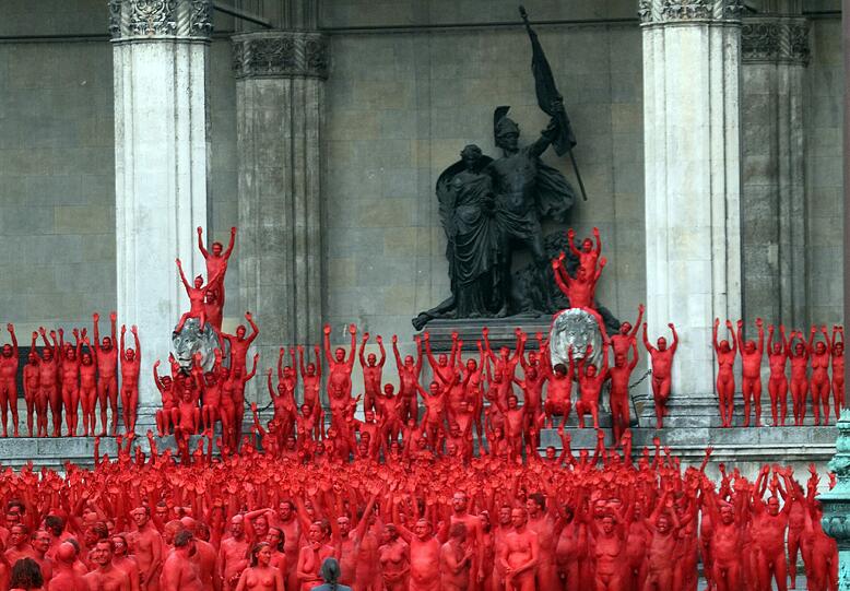 Star-Fotograf Spencer Tunick lässt zur Eröffnung der Opernfestspiele für seine Installation hunderte bunt angemalte Menschen durch München laufen. Das Highlight: Die rot-goldenen Teilnehmer stellen sich an Münchner Monumenten entlang der Ludwigstraße auf. Hier gibts die Bilder!