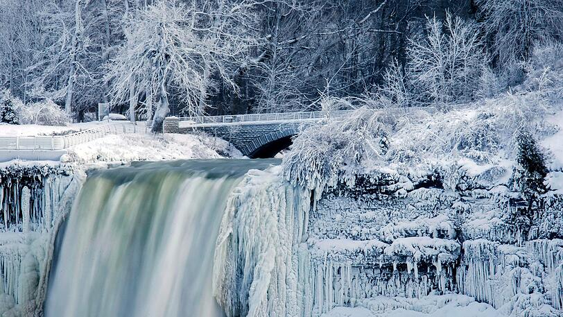 Wasser fällt in Niagara Falls, New York, USA, die Bridal Veil Falls hinab, während die Umgebung in Eis gehüllt ist.