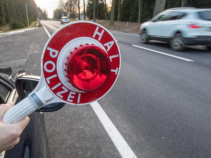 Ein Polizist hält eine Polizeikelle. Foto: Armin Weigel/Archiv