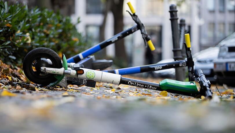 E-Scooter liegen auf einem Gehweg und versperren den Weg.