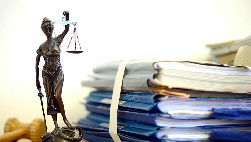 Eine Figur der Justitia, der altrömischen Göttin der Gerechtigkeit, neben einem Stapel Gerichtsakten. (Symbolbild) Eine Figur der Justitia, der altrömischen Göttin der Gerechtigkeit, neben einem Stapel Gerichtsakten. (Symbolbild)