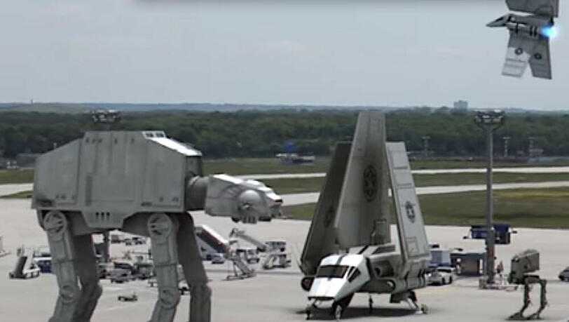 AT-AT Walker stapfen zwischen "Starport"-Bussen über das Rollfeld AT-AT Walker stapfen zwischen "Starport"-Bussen über das Rollfeld