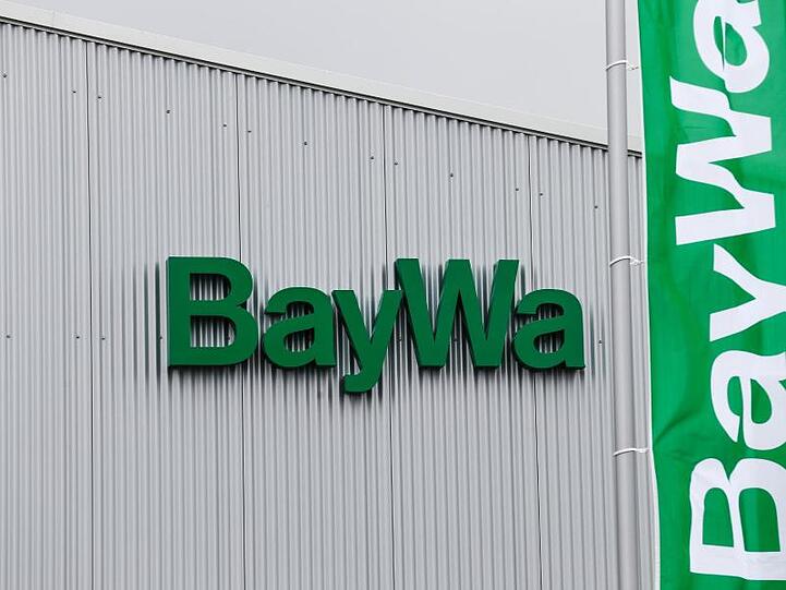 BayWa-Fahnen wehen vor einem der BayWa AG, auf dem das Logo von BayWa zu sehen ist. Foto: David Ebener/Archiv