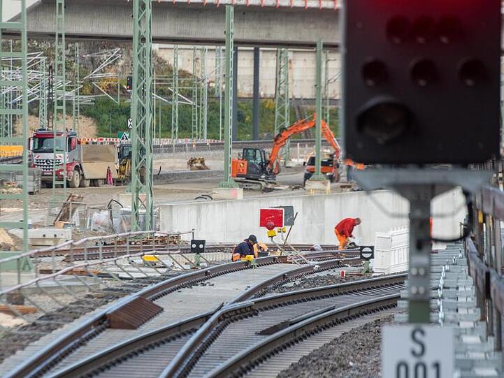 Ein Zug fährt im Hauptbahnhof an Gleisbauarbeitern vorbei. Foto: Stefan Puchner/dpa