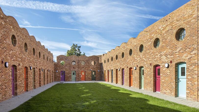 Bunte Türen, Backstein, Himmel: der Innenhof der Holmes Road Studios von Peter Barber Architects in London. Bunte Türen, Backstein, Himmel: der Innenhof der Holmes Road Studios von Peter Barber Architects in London.