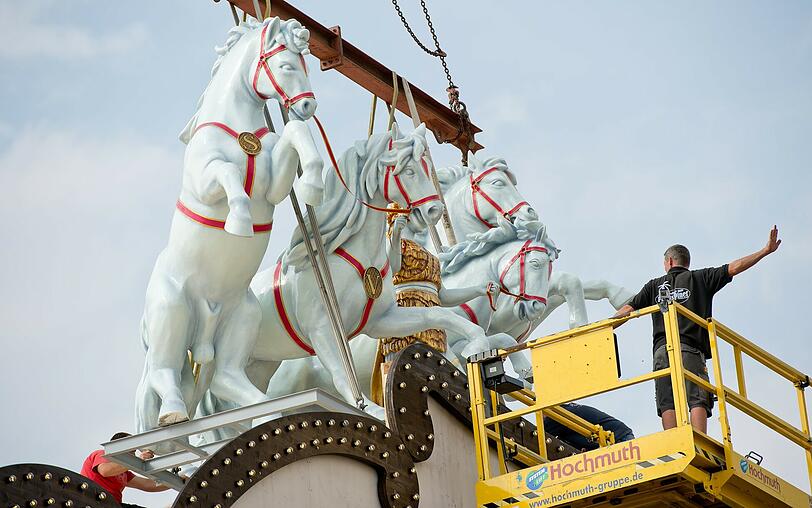 Die Bavaria zügelt vier wilde Schimmel auf dem Dach des Marstall-Zeltes.