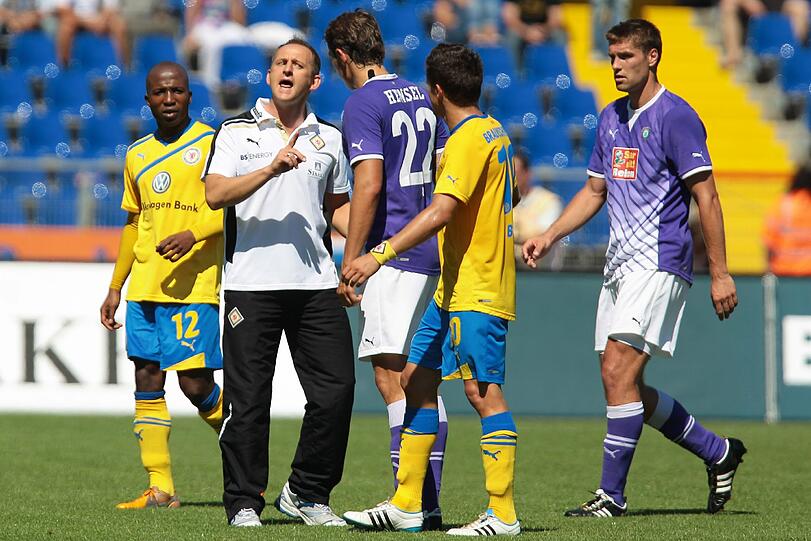 raunschweigs Trainer Torsten Lieberknecht (2.v.l.) diskutiert in der Halbzeitpause mit Aues Marc Hensel (3.v.l.).