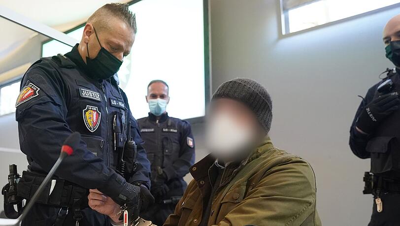 Ein Justizbeamter entfernt die Handschellen des Angeklagten (2.v.r) im Sitzungssaal des Landgerichts Kiel.