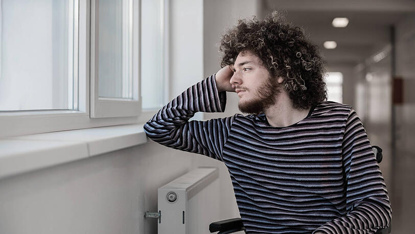Ein junger Mann sitzt in einem Rollstuhl und sieht aus dem Fenster eines Krankenhauses. Das psychische Leiden von Krebspatienten wird oft übersehen, berichten zwei junge Münchnerinnen. Ein junger Mann sitzt in einem Rollstuhl und sieht aus dem Fenster eines Krankenhauses. Das psychische Leiden von Krebspatienten wird oft übersehen, berichten zwei junge Münchnerinnen.