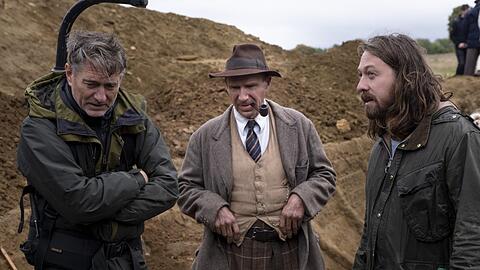 Am Set von "Die Ausgrabung", einem Archäologen-Thriller: Ralph Fiennes als Basil Brown mit dem Regisseur Simon Stone (rechts), der auch am Münchner Residenztheater Regie führt. Links: Kameramann Mike Eley.