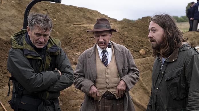 Am Set von "Die Ausgrabung", einem Archäologen-Thriller: Ralph Fiennes als Basil Brown mit dem Regisseur Simon Stone (rechts), der auch am Münchner Residenztheater Regie führt. Links: Kameramann Mike Eley.
