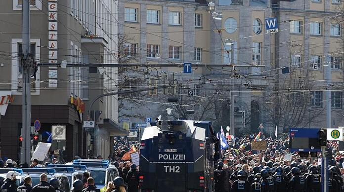 Einsatzkräfte der Polizei stehen bei einer Kundgebung unter dem Motto "Freie Bürger Kassel - Grundrechte und Demokratie" neben einem Wasserwerfer.
