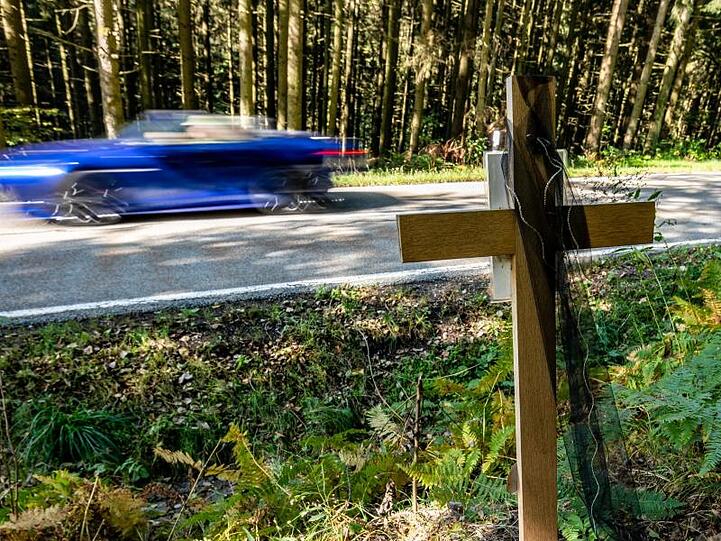 Ein Holzkreuz steht bei Achslach an der Stelle, an der die Männer bei einem Rennen den Tod eines weiteren Autofahrers verursacht haben sollen.