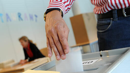 Ein Mann wirft am Sonntag in München einen Stimmzettel in eine Wahlurne. Ein Mann wirft am Sonntag in München einen Stimmzettel in eine Wahlurne.