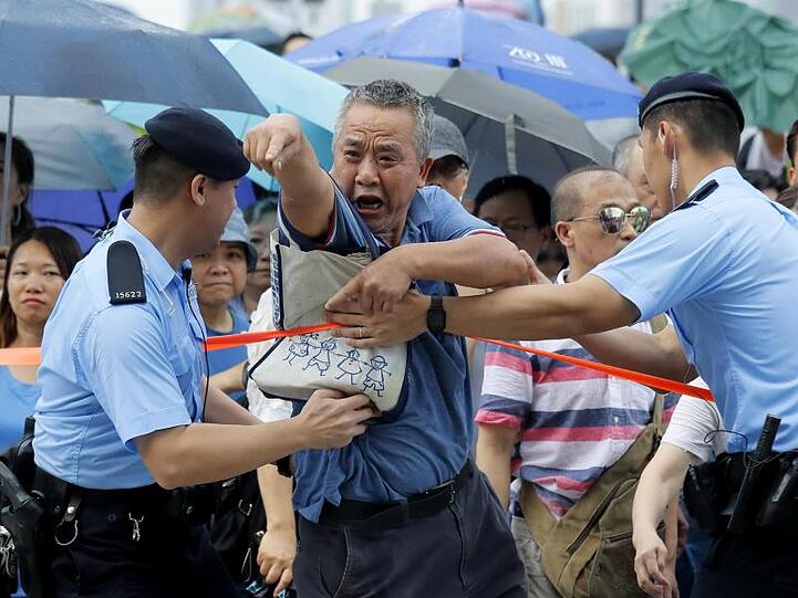Gegenprotest: Ein pro-chinesischer Demonstrant wird während einer Kundgebung von Polizisten zurückgehalten.