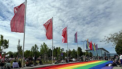 Eine &uuml;bergro&szlig;e Regenbogenfahne liegt ausgebreitet neben einer Kundgebung des DGB in Erfurt