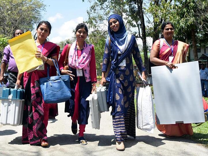 Indische Helferinnen bringen Wahlautomaten und -material in ihre Wahllokale. Wahlberechtigt sind rund 900 Millionen Menschen.