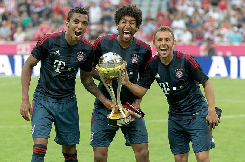 Luiz Gustavo und Dante (hier mit Rafinha und dem Uli-Hoeneß-Cup) reisen am 14. August in die Schweiz. Beim Testspiel der brasilianischen Nationalmannschaft gegen die Schweiz stehen sie auf dem Platz.