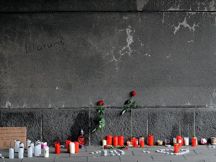 Kerzen, Rosen und ein Schild stehen in dem Tunnel - der Eingang, der für viele Menschen zum Verhängnis wurde