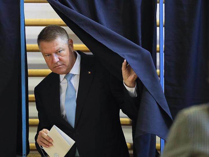 Klaus Iohannis, Präsident von Rumänien, verlässt eine Wahlkabine mit einem Stimmzettel.